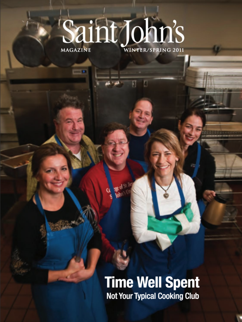A group of six people in blue aprons stand in a commercial kitchen. They are smiling and appear to be part of a cooking club. The text reads: "Saint John's Magazine Winter/Spring 2011 - Time Well Spent: Not Your Typical Cooking Club.